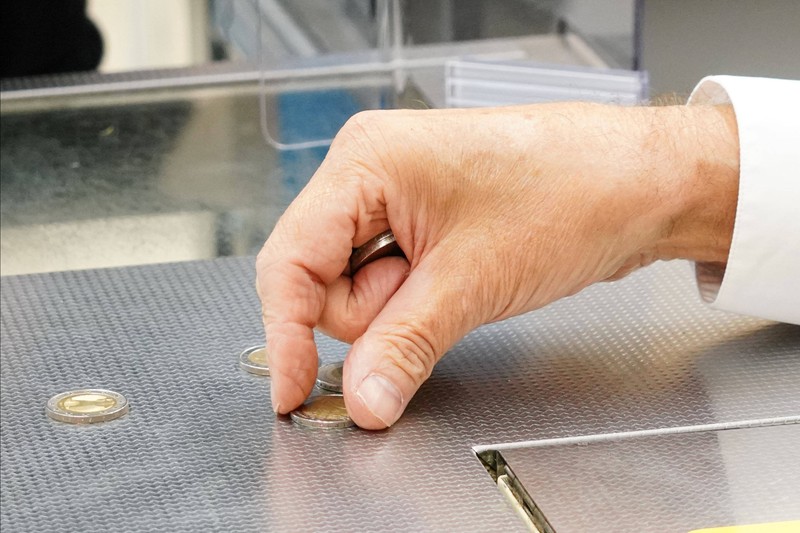 Zu sehen ist die Hand eines Kassierers, der Geldstücke aufnimmt.