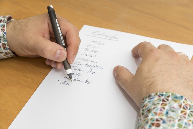 Zu sehen ist eine Person, die einen Einkaufszettel schreibt.