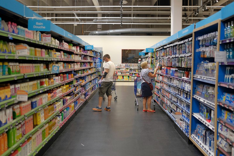 Zu sehen sind zwei Menschen, die vor Regalen im Supermarkt stehen.