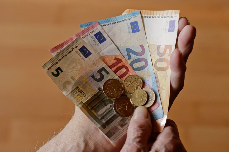 Zu sehen sind Hände, die Euro-Banknoten und Münzen in der Hand halten.