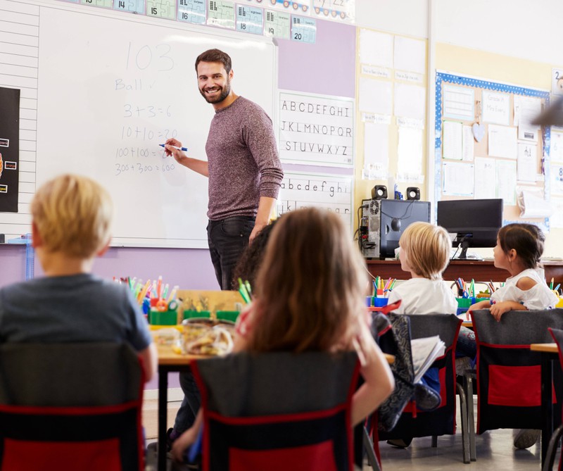 Ein junger attraktiver Lehrer vor seiner Klasse.