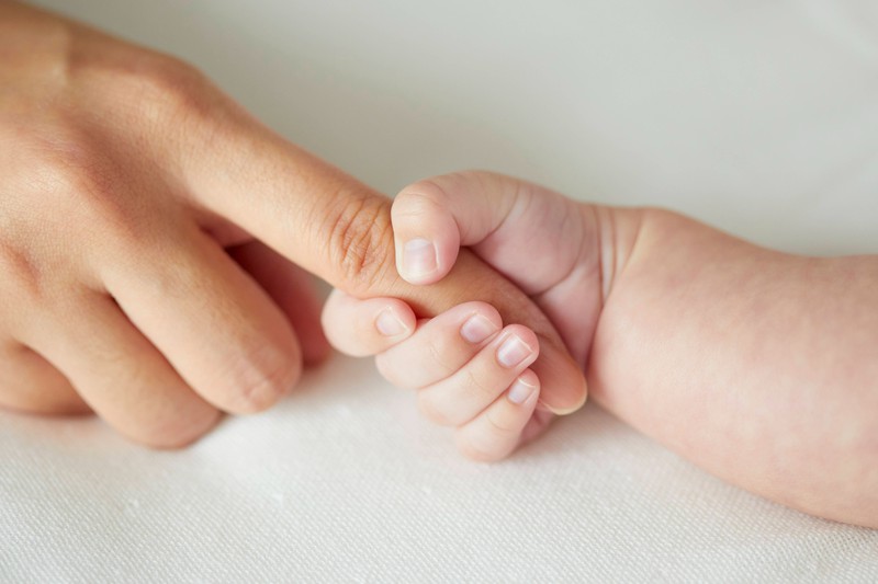 Eine Babyhand hält einen Finger