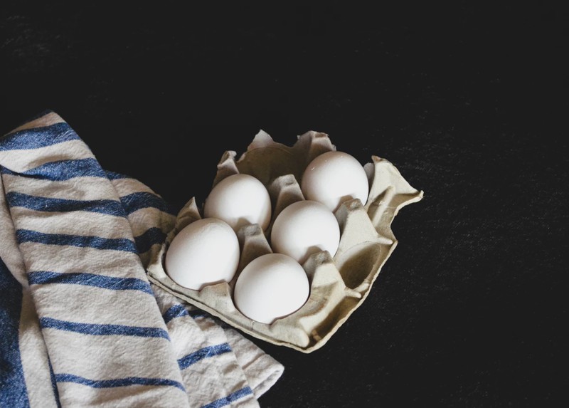 Weiße Eier in Papierverpackung neben Handtuch