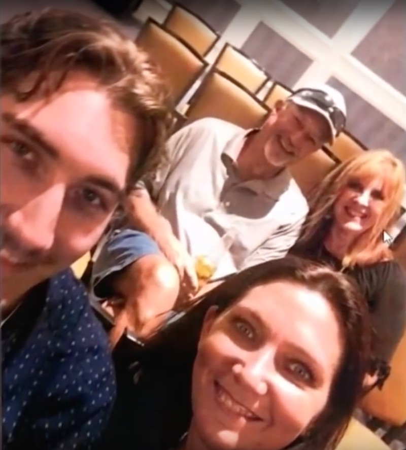 Auf dem Bild sind vier Personen zu sehen, die lächelnd in die Kamera posieren.