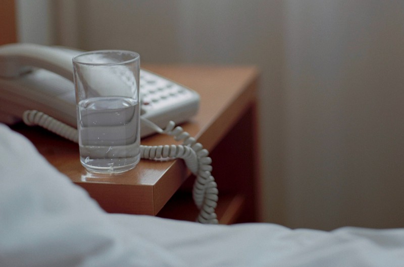 Halbvolles Glas Wasser auf dem Nachttisch neben dem Bett.