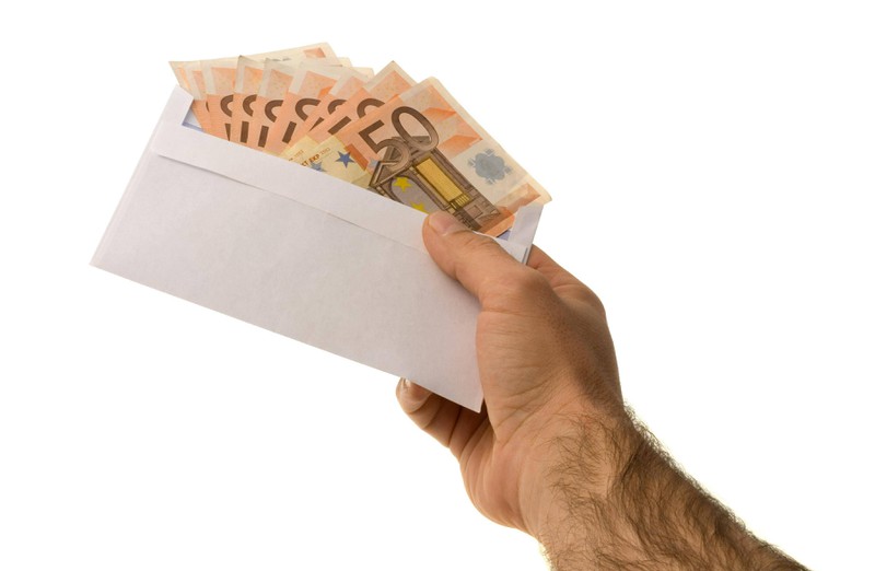Hand hält einen Umschlag mit 50 Euro-Scheinen