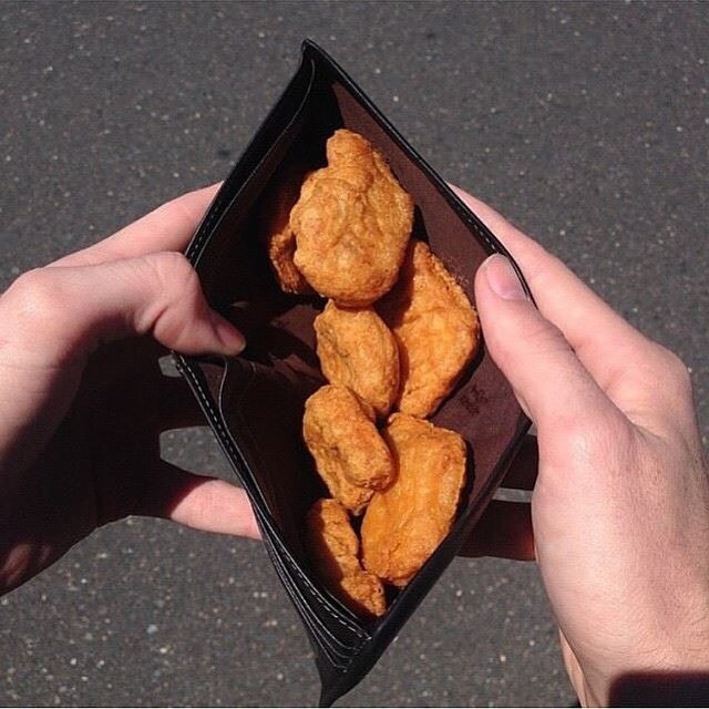Zu sehen ist eine Brieftasche, in der Chicken Nuggets liegen.