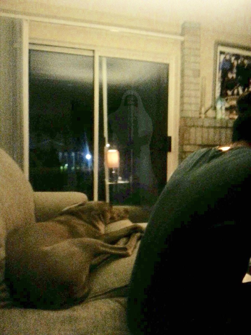 Man sieht ein Wohnzimmer und im Hintergrund steht ein Geist.