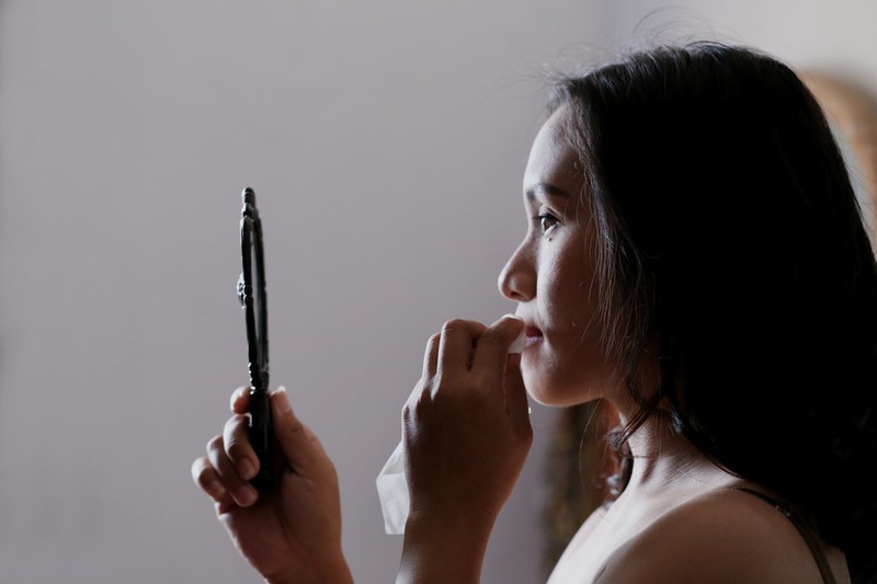 Dieses Bild zeigt eine Frau, die ihre Haut im Spiegel inspiziert.