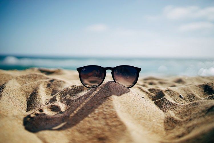 Man sieht eine Sonnenbrille im Sand und es geht um Tipps bei Hitze.
