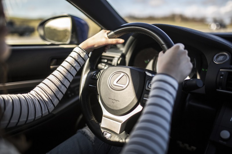 Dieses Bild zeigt eine Frau, die im Auto am Steuer sitzt.