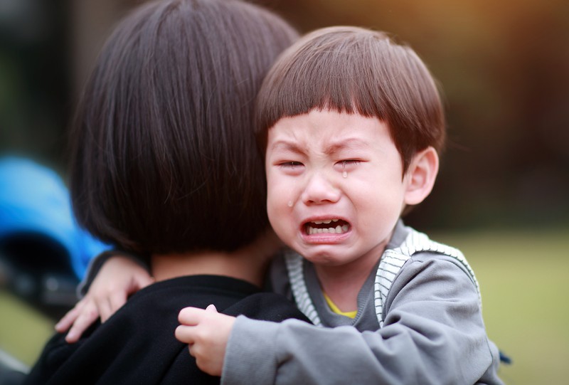 Kleiner Junge weint auf Mutters Arm