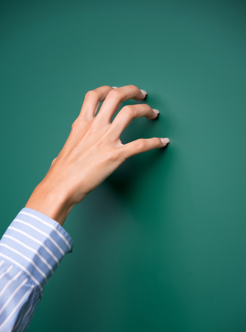 Hand kratzt über Tafel