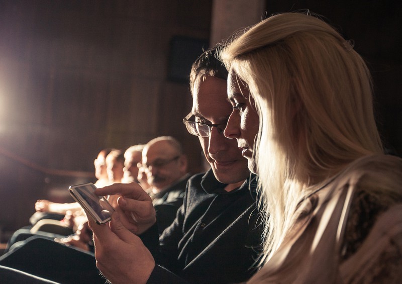 Paar schaut im Kino auf Handy
