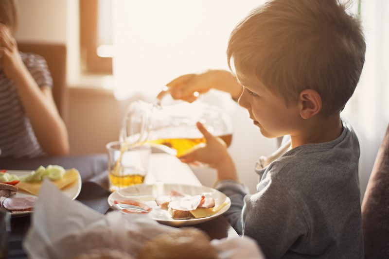 Kind gießt Apfelsaft ein