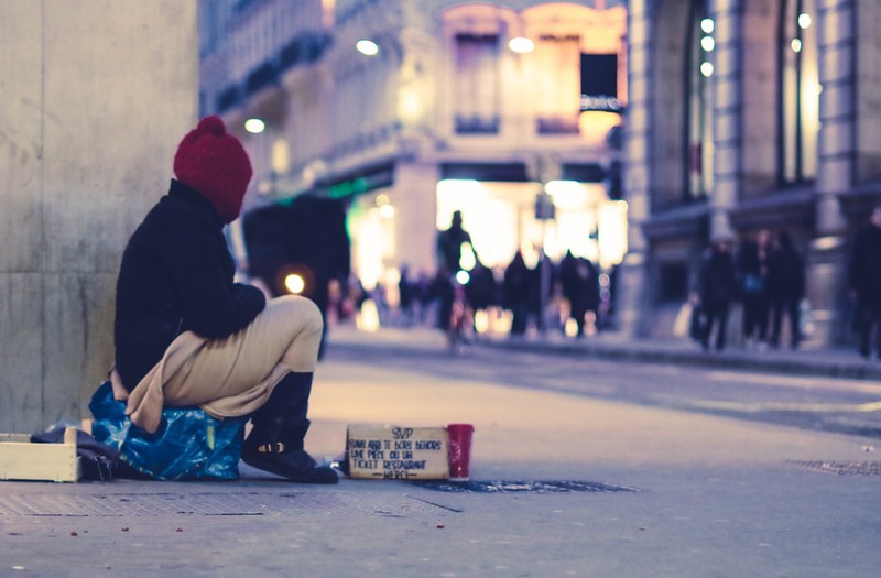 Obdachlose Person sitzt auf der Straße