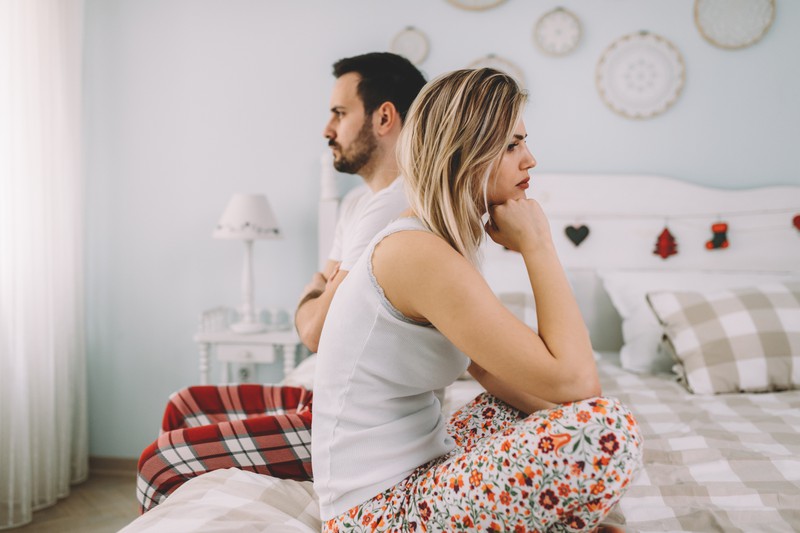 Paar sitzt zerstritten auf dem Bett