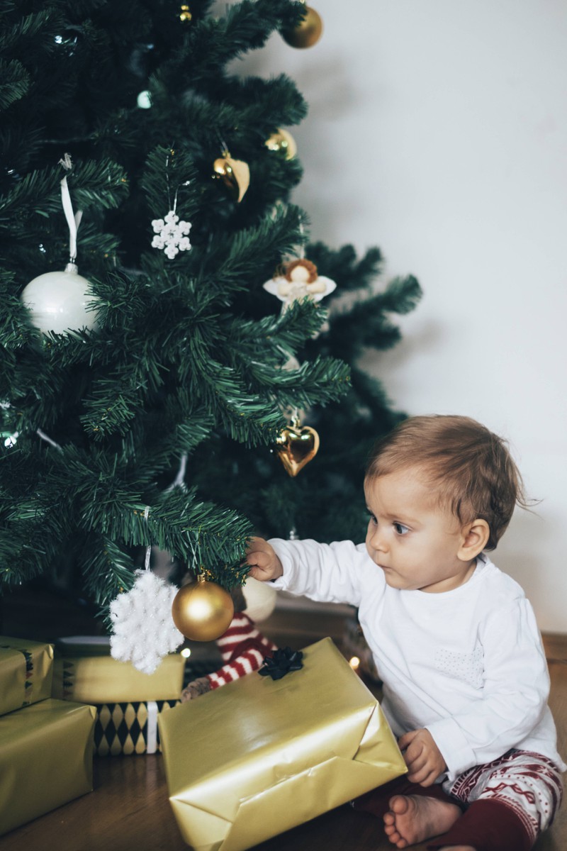 Man sieht ein Kleinkind mit einem Weihnachtsgeschenk, vermutlich ein Spielzeug