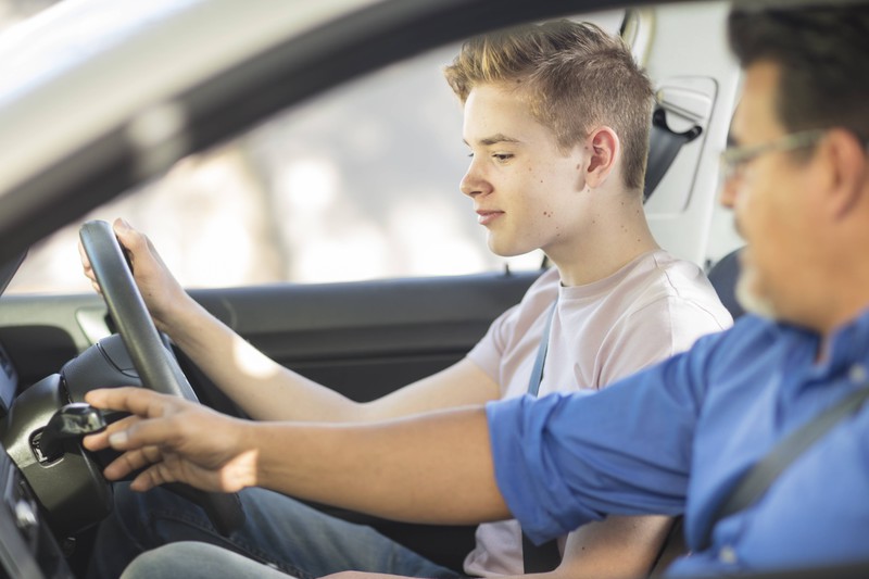 Ein Fahrschüler sitzt im Auto am Steuer neben seinem Prüfer