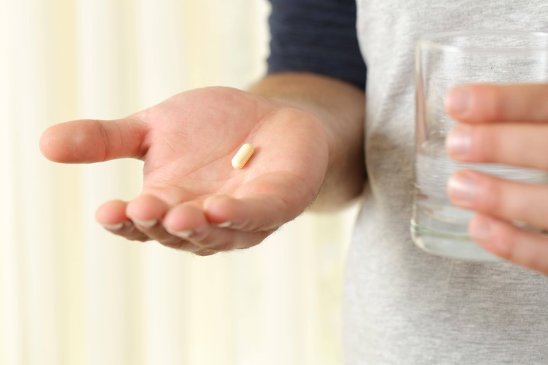 Patient hält eine Vitamin-Kapsel in der Hand