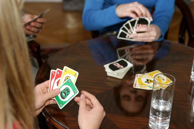 Menschen spielen UNO Karten, aber die Macher lösen eine Regel auf.
