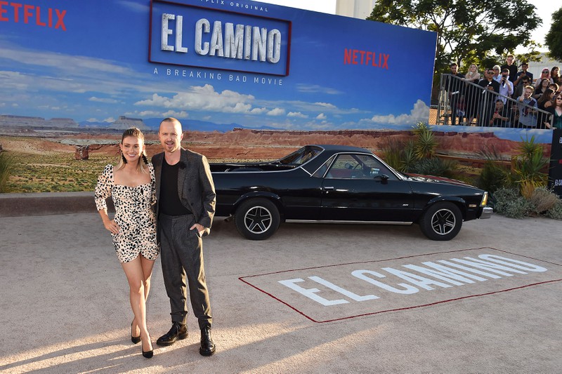 Aaron Paul steht vor Leinwand zu seinem neuen Film El Camino der auf Netflix läuft, Aaron Paul äußerte sich kritisch gegenüber der neuen Möglichkeit, Filme auf Netflix schneller abspielen zu können