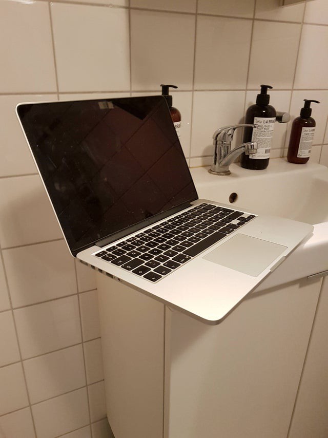 Ein Laptop balanciert auf dem Rand eines Waschbeckens, was bei uns ein unbehagliches Gefühl auslöst.