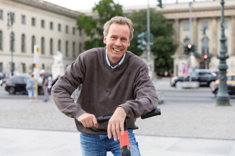 Man sieht einen Mann, der mit dem E-Scooter fährt