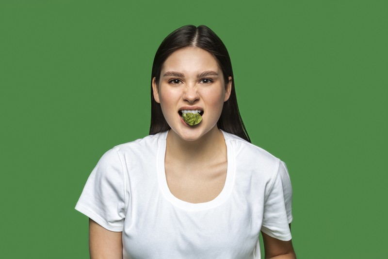 Eine junge Frau, die etwas isst, dass sie anscheinend anekelt.