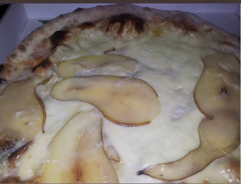 Man sieht eine Pizza dessen Belag Birnenscheiben sind.