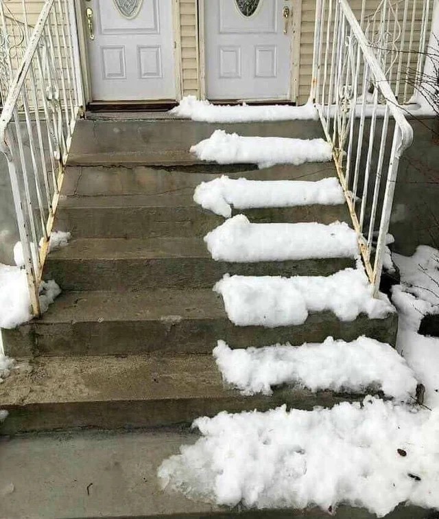 Man sieht eine Treppe vor einem Haus, wo ein Nachbar nur die eine Hälfte den Schnee geschaufelt hat