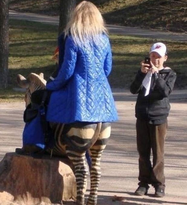 Ein Junge macht ein Foto einer Frau, bei der es aussieht, als hätte sie einen Zebra-Hintern.