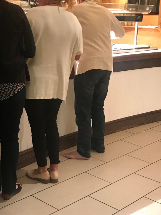 Besucher im Restaurant steht mit nackten Füßen am Buffet