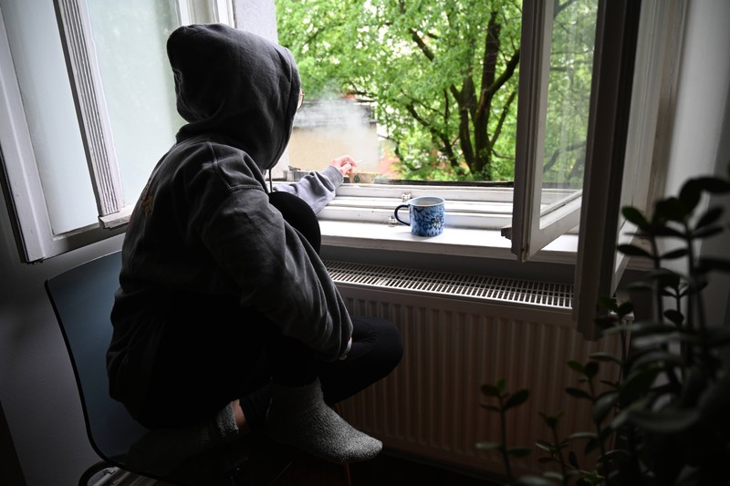 Ein Foto einer Frau die am Fenster in der Wohnung raucht und aufgrund des Wlan Routers aufgeflogen ist