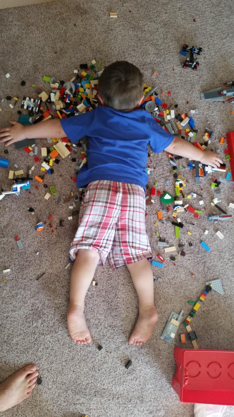 Der kleine Junge wurde müde und ist bereit überall zu schlafen, auch auf dem Fußboden und Lego.