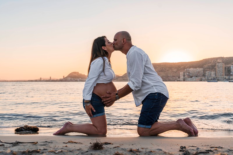 Ein Paar erwartet ein Baby, sie küssen sich am Strand