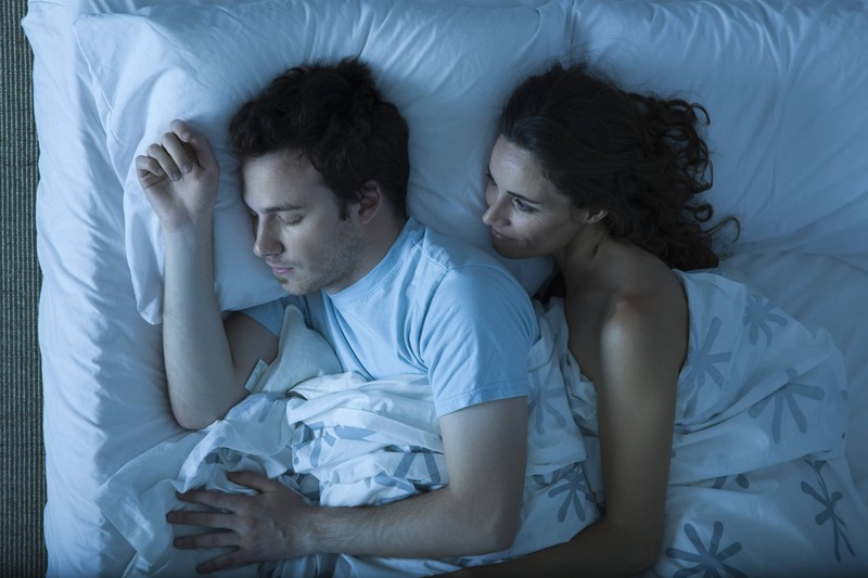 Ein Paar, das im Bett schläft und die Frau plötzlich eine Stimme hört