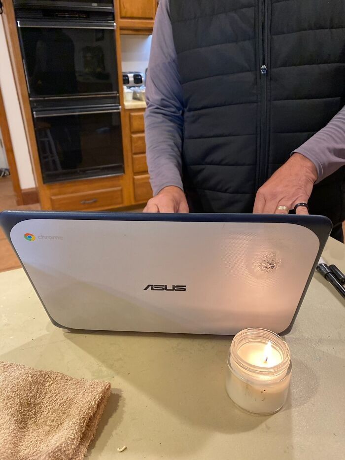 Mann verbrennt den oberen Rand seines Laptops mit einer Kerze