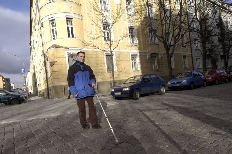 Mann mit Seheinschränkungen überquert die Straße
