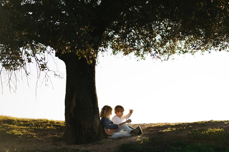 Zwei Kinder sitzen im Schatten eines Baumes