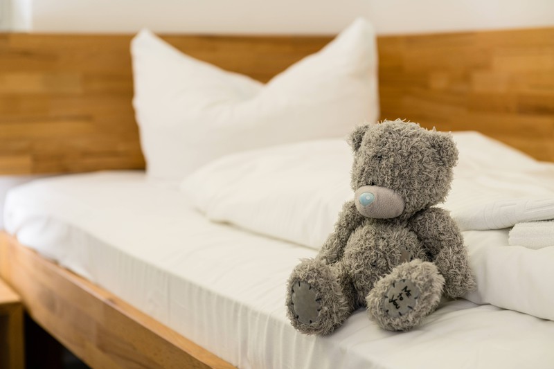 Ein Teddybär sitzt auf einem Bett