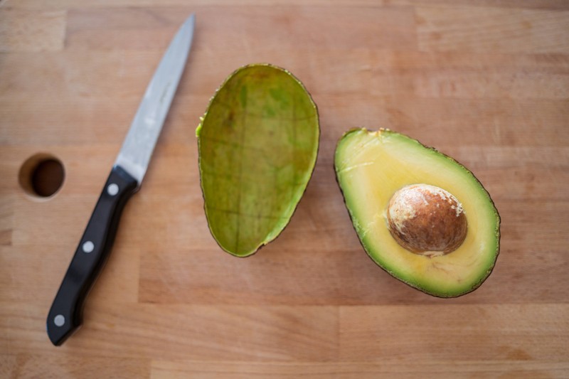 Eine Avocado sollte man nicht in zwei Teile, sondern in vier Teile schneiden, damit man die Frucht vom Kern lösen kann.